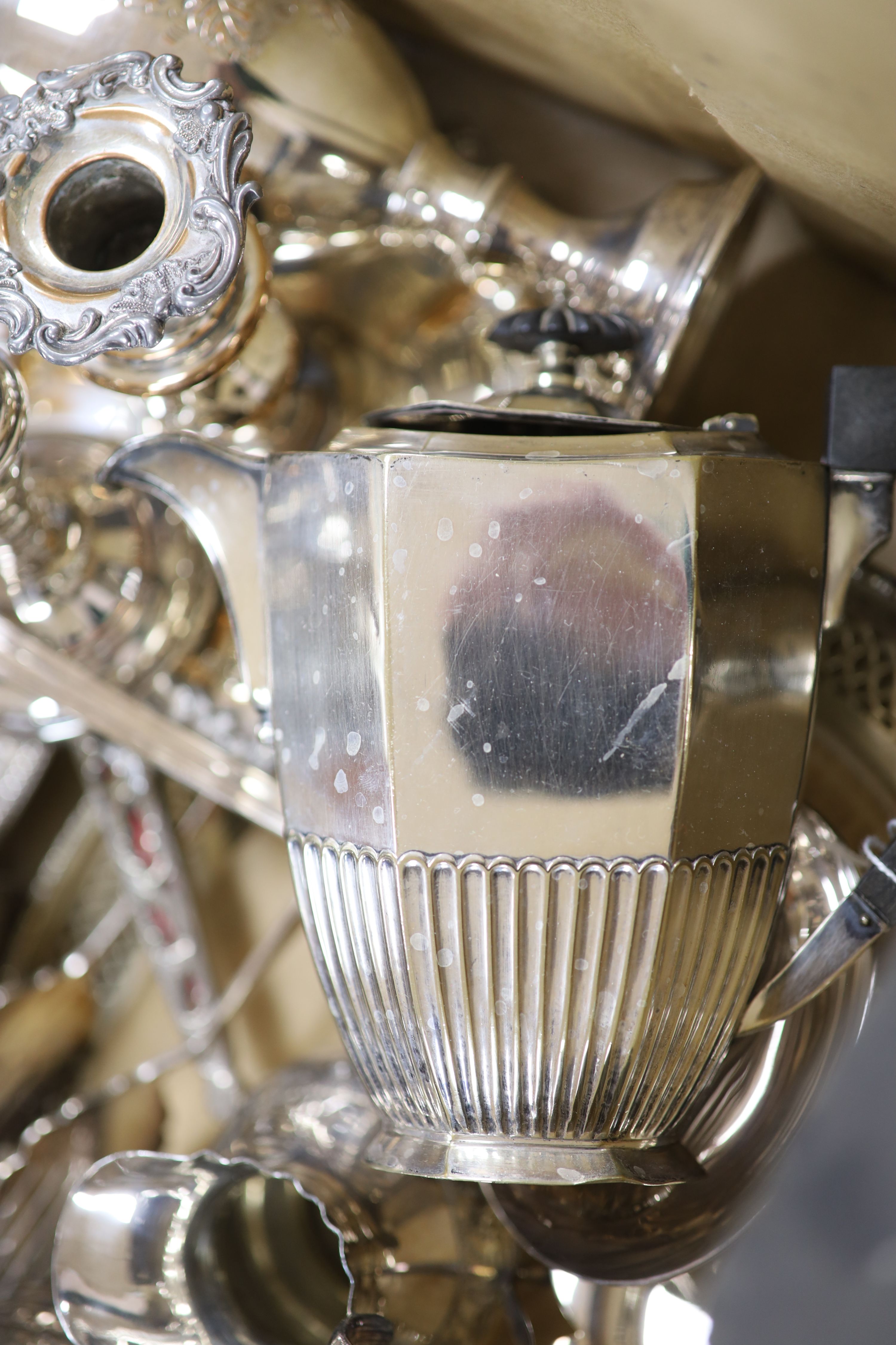 A quantity of assorted plated wares including a chamberstick, a tea set, flatware, a cocktail shaker, a sauceboat, goblets etc.